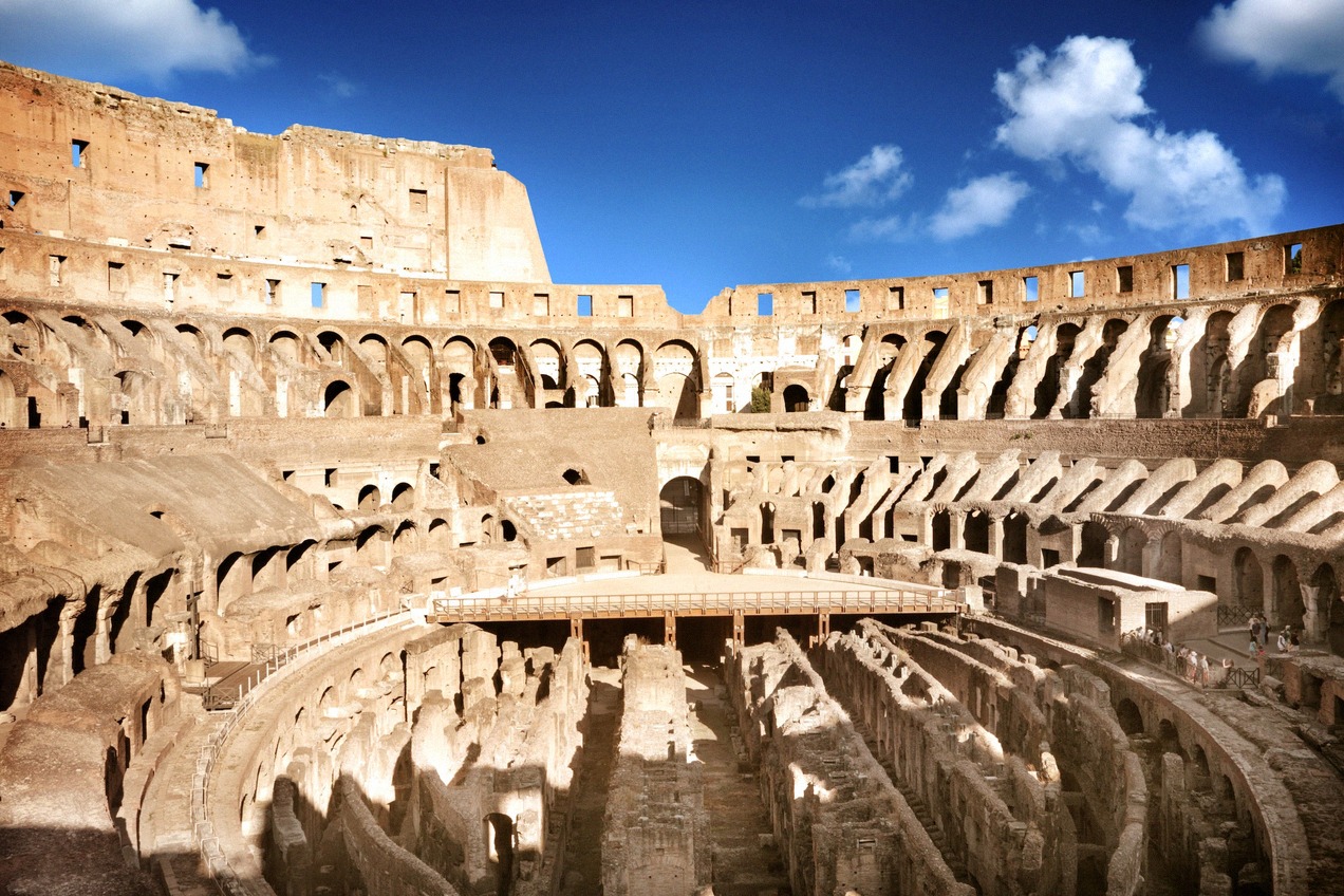 Inside the Colosseum in Rome, the arena floor and the exposed underground corridors seen from the stands.