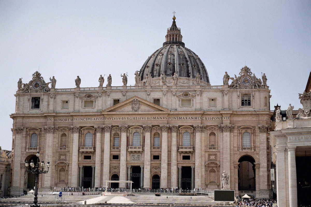 The facade of St Peter's Basilica in the Vatican with the dome behind it.